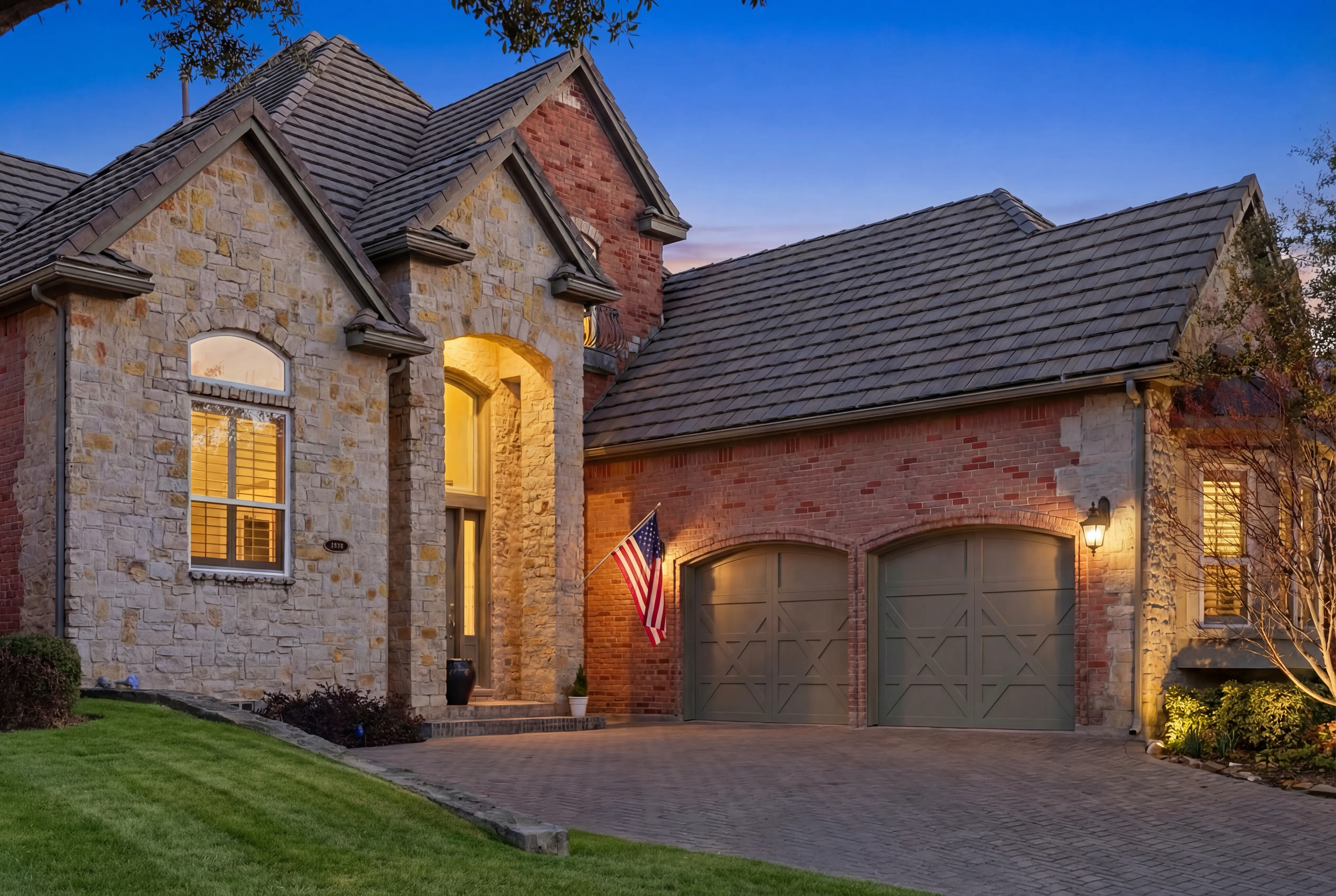 Stone and brick exterior with paver driveway and professional landscaping